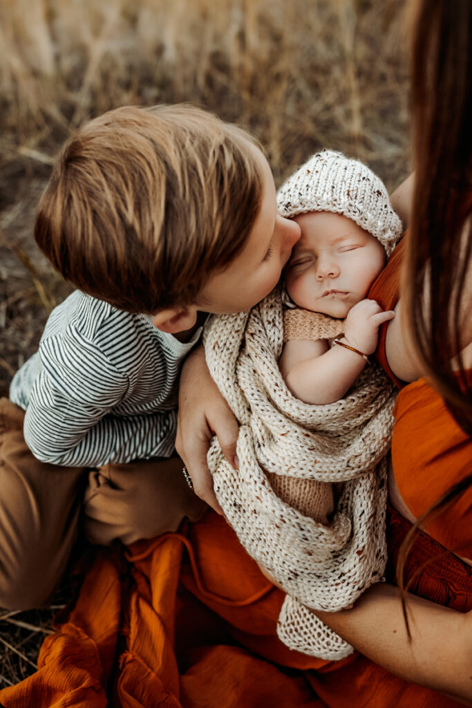 Family Photography, Mom holding newborn baby, toddler kissing baby's cheek